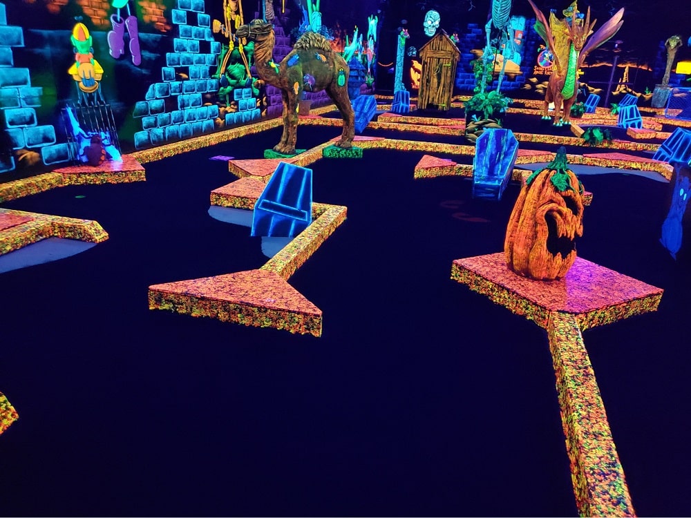 A mini golf course filled with fake monsters under neon lights at Monster Mini Golf.