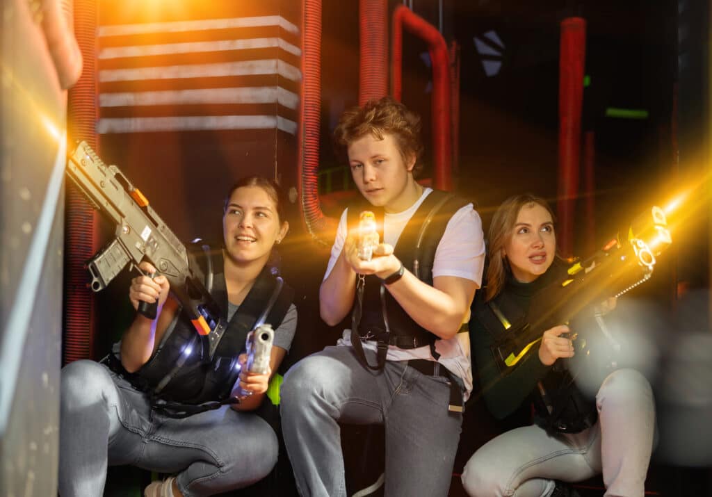 Group of people with laser pistols playing laser tag in the dark