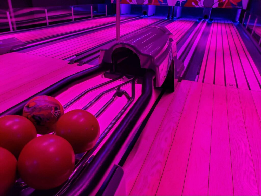 Neon pink bowling lanes with mini bowling balls at Monster Mini Golf.  