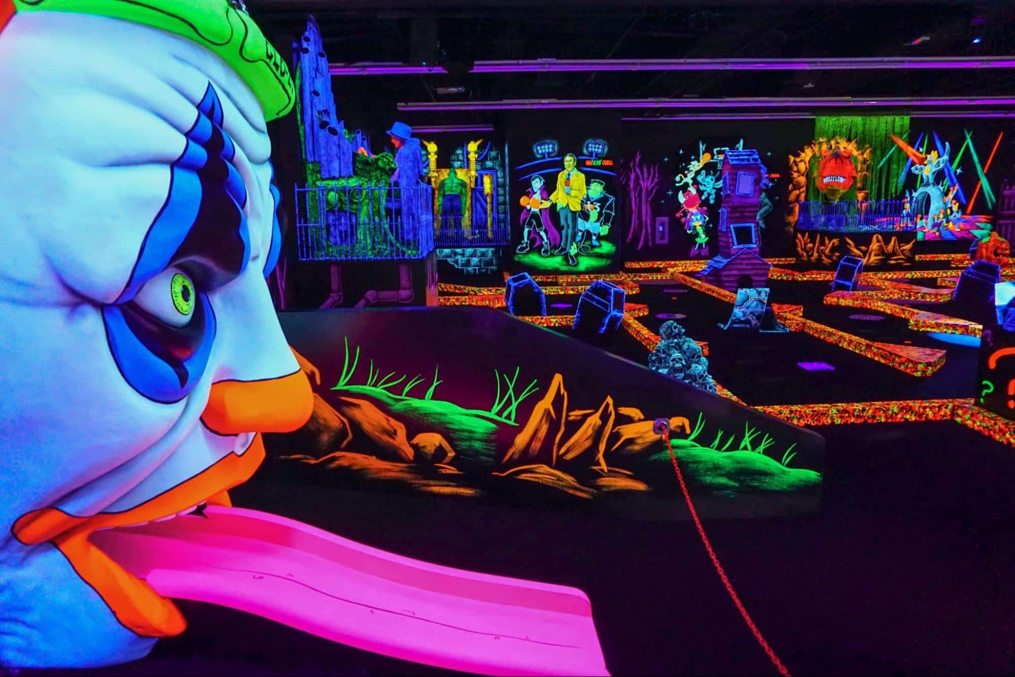 A clown decoration on a glow-in-the-dark mini golf course