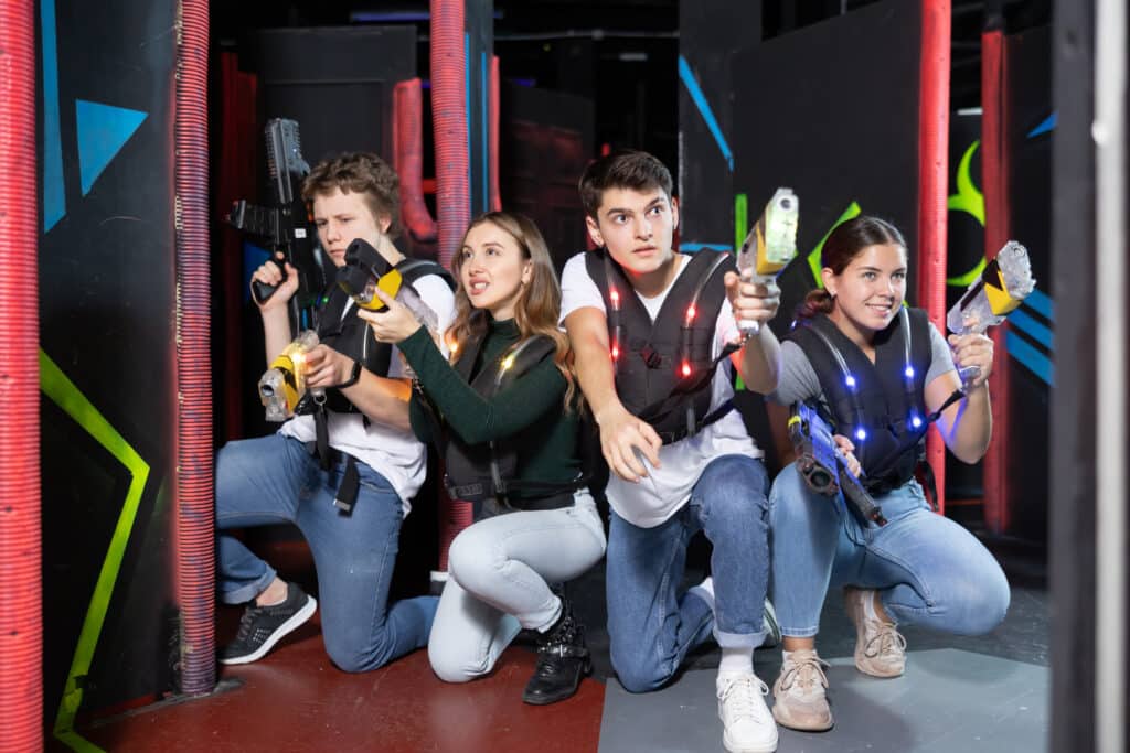 Group playing laser tag game opposite each other in modern dark room