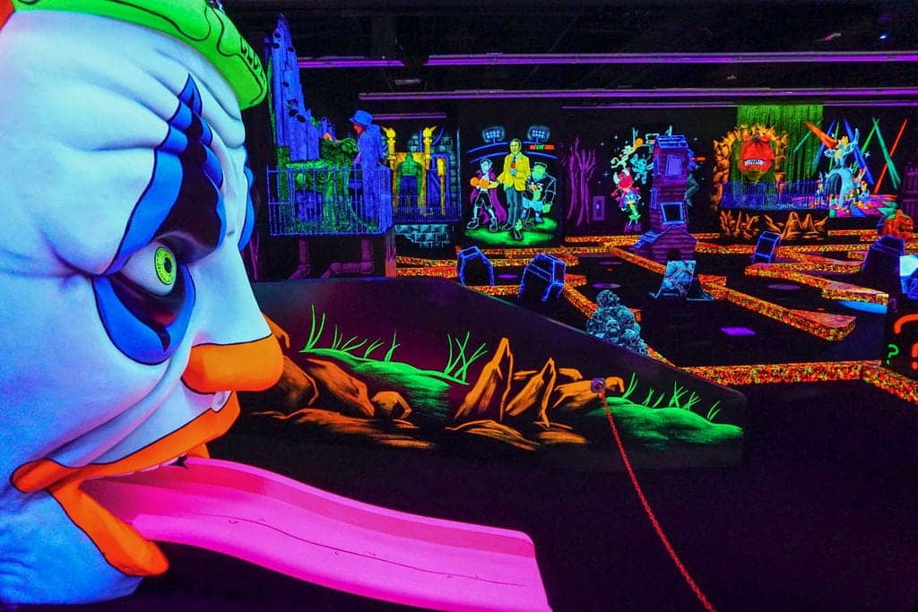 A neon clown decoration at an indoor mini golf course at a Monster Mini Golf location. 