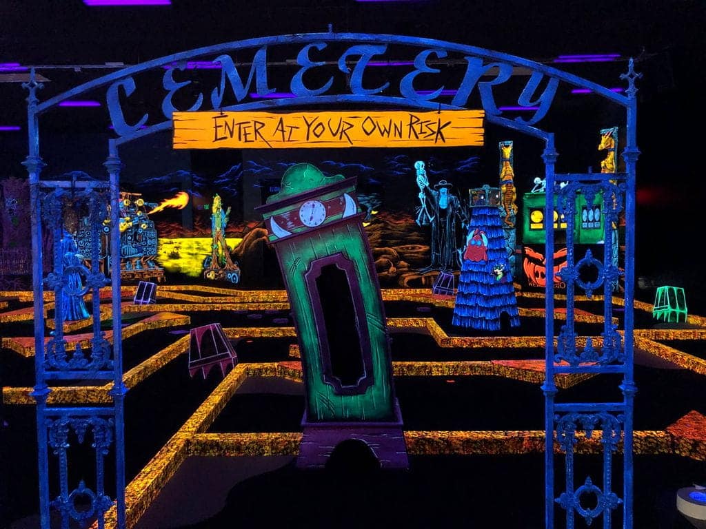 A neon entrance to a Monster Mini Golf indoor mini golf course location.