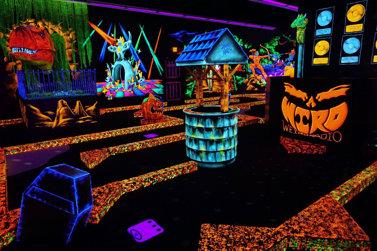 A neon glow-in-the-dark indoor mini golf course at a monster mini golf location.